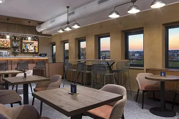 Bar del DoubleTree by Hilton Rome Monti con grandi finestre affacciate sulla città al tramonto