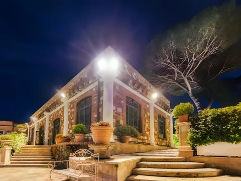 Facciata di Villa dei Cesari illuminata di sera, con la scalinata d’ingresso